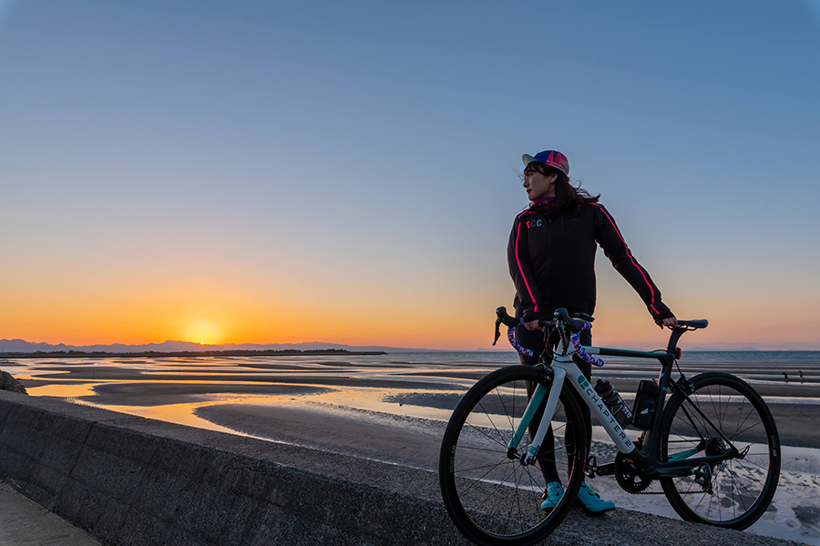 真玉海岸の夕陽を眺める女性サイクリスト